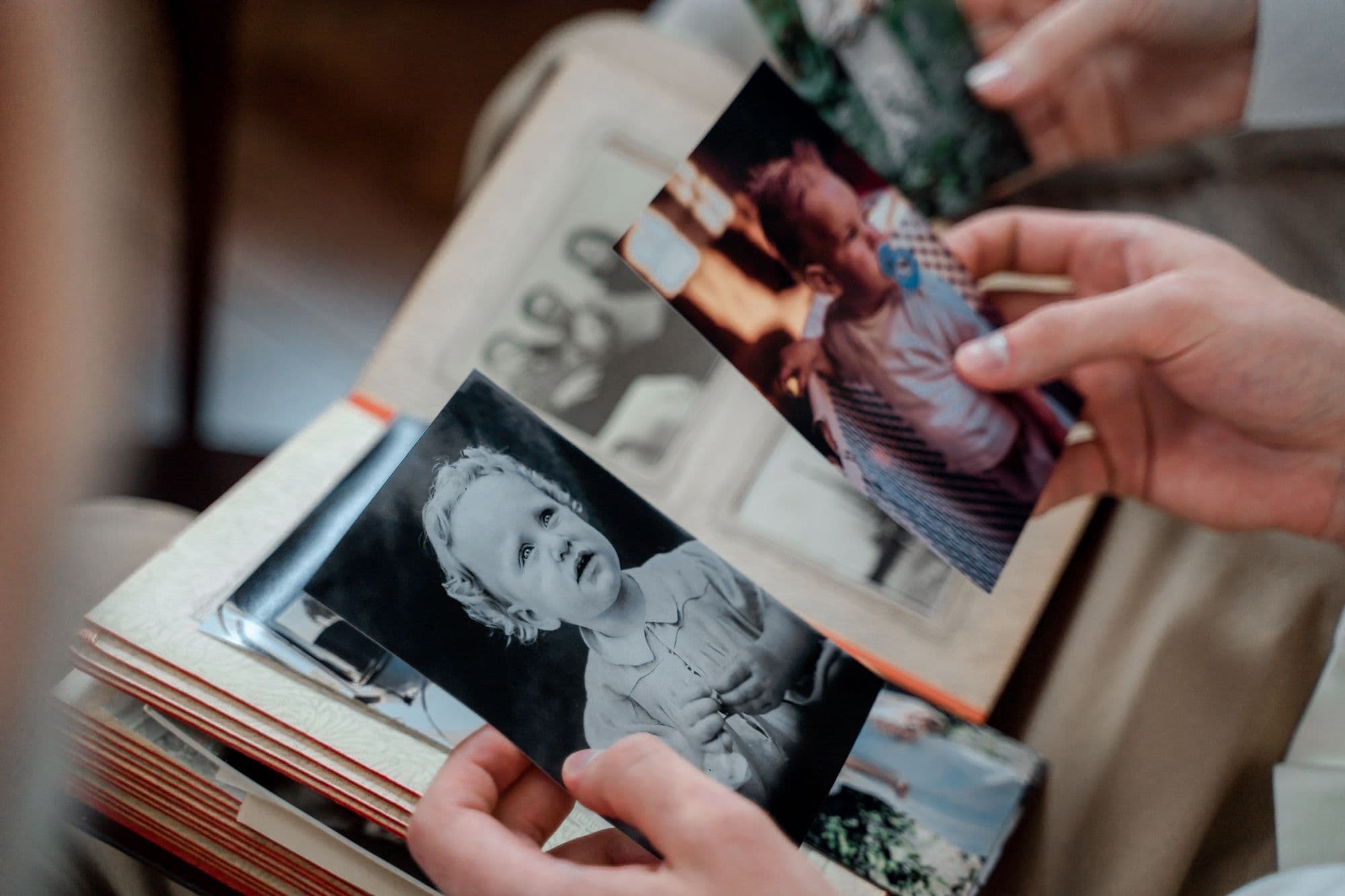 Hands holding old black-and-white family photographs over an album