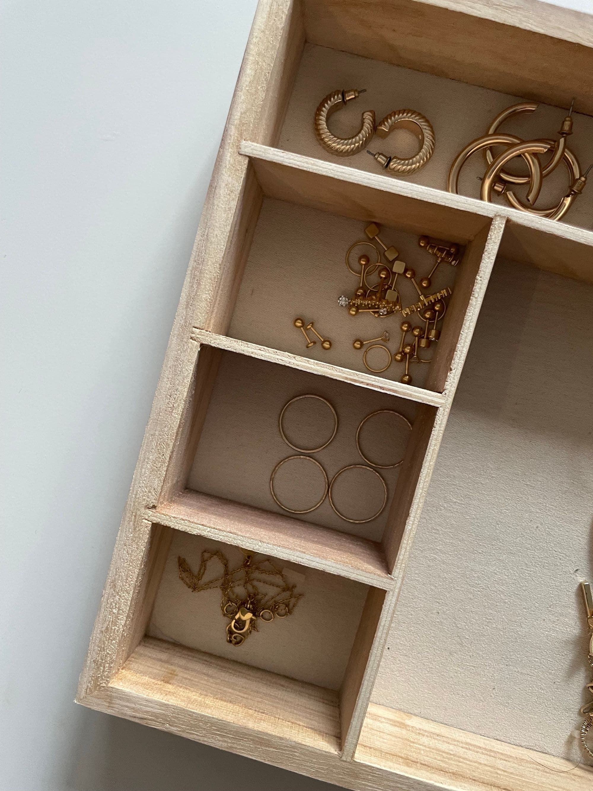 Gold rings and earrings in a wooden tray with compartments