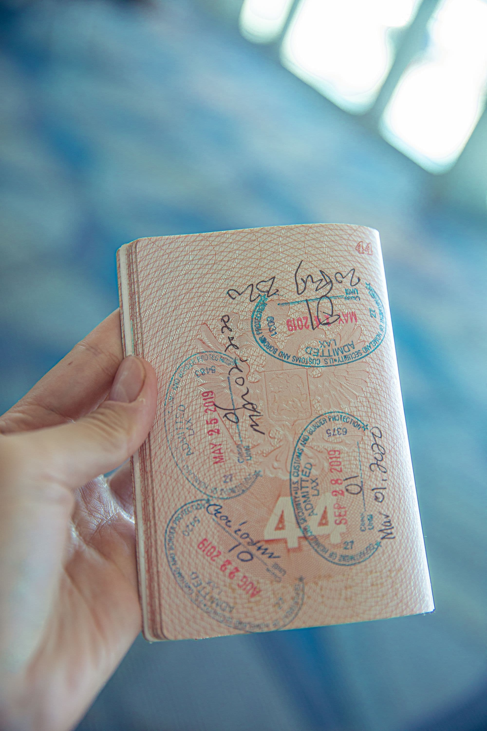 A hand holding a passport with stamped pages